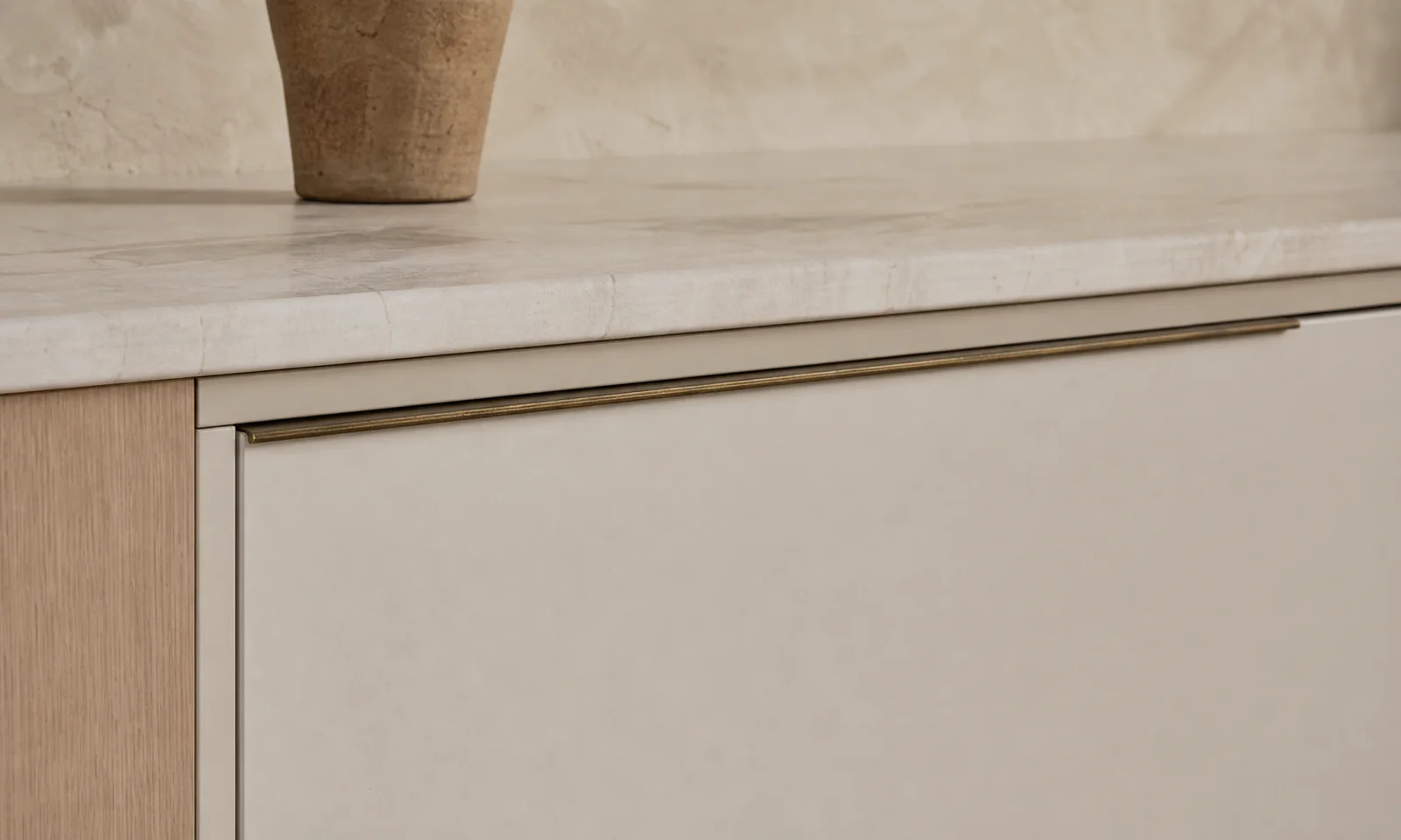 Velora concept — a fine aged-brass edge pull on a matte front